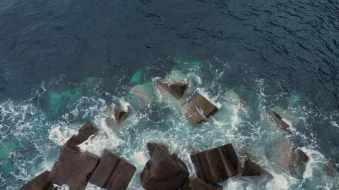 Aerial view of powerful ocean waves crashing against concrete breakwater blocks Vidéo 345960669