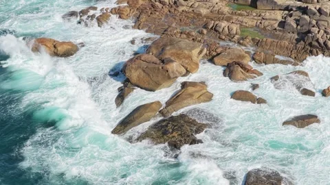 Aerial view of powerful ocean waves crashing against large rugged rocks on the Stock Footage 346705628