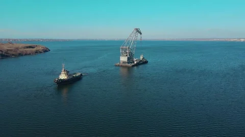 Aerial view powerful tugboat pulling large floating barge with mounted crane by Stock Footage 172470460