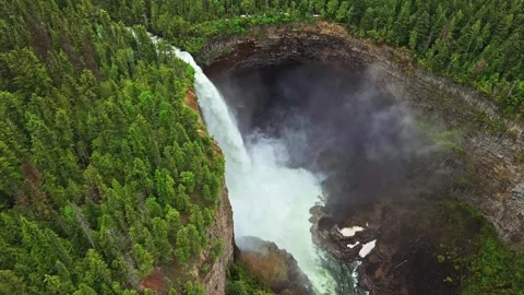 Aerial view of powerful waterfall cascading down steep cliff into canyon with fo Stock Footage 344137761