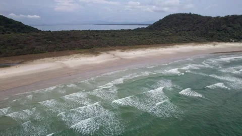 Aerial View of Pristine Beach with Forested Hills and Ocean Waves Stock Footage 336452494