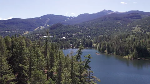 Aerial view of pristine mountain lake on sunny day against mountain backdrop Stock Footage 250952859