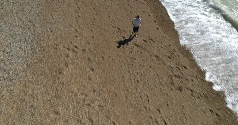 Aerial view of professional athlete training running on a beach by the sea Stock Footage 80871727