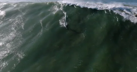 Aerial view of a professional big wave surfer on a big wave in Nazare surfing Stock Footage 224910477