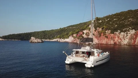Aerial view, pull back from a Catmaran Sailboats anchored in a calm blue lonely Stock Footage 96356904