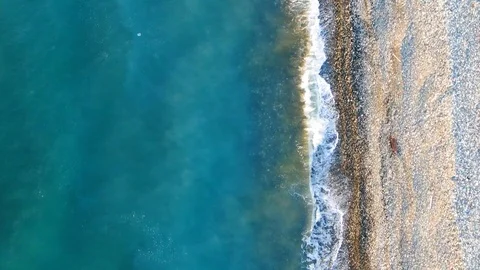 Aerial view of pulling back over the beach as turquoise sea waves gently Stock Footage 120759960
