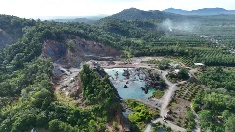 Aerial view of a quarry lake surrounded by lush greenery and mountains Stock Footage 334646647