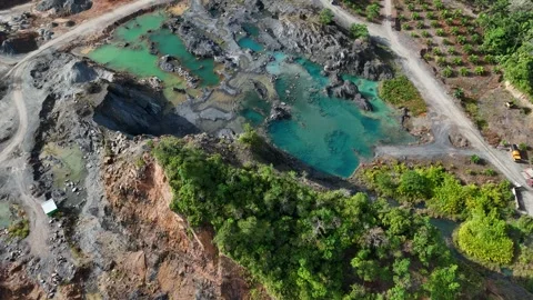 Aerial view of a quarry lake surrounded by lush greenery and mountains Stock Footage 334646673
