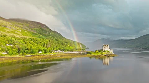 Aerial view of a rainbow over Eilean Donan Castle with long arched bridge. Stock Footage 283495494
