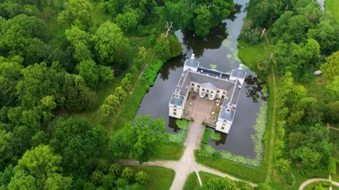 Aerial view of a rectangular, four tower castle surrounded by a moat and dense Видео 317542453