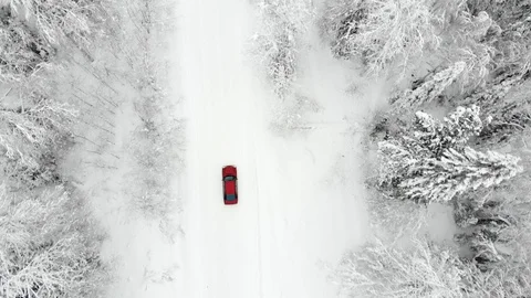 Aerial view of red car driving empty white dirt road in winter snowy forest Stock Footage 122425688