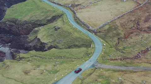 Aerial view of red car moving on beautiful curved costal road Stock Footage 101539090