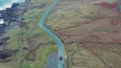 Aerial view of red car moving on beautiful curved costal road Stock Footage 101539257