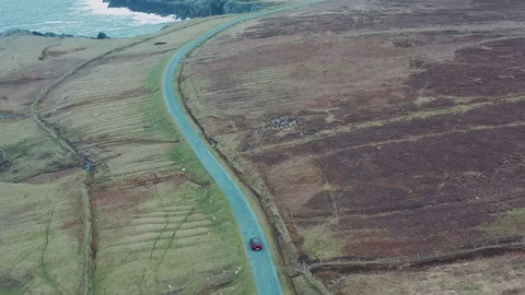 Aerial view of red car moving on beautiful curved costal road Stock Footage 101540294