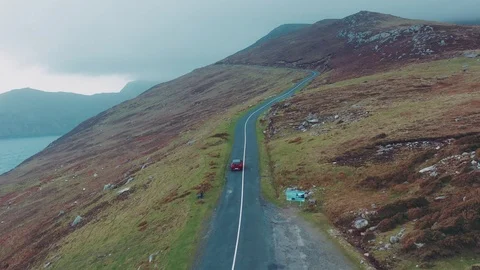 Aerial view of red car moving on beautiful curved costal road Stock Footage 101541679