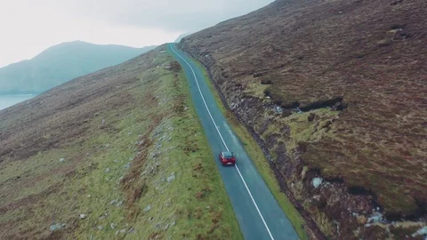 Aerial view of red car moving on beautiful curved costal road Stock Footage 101543531