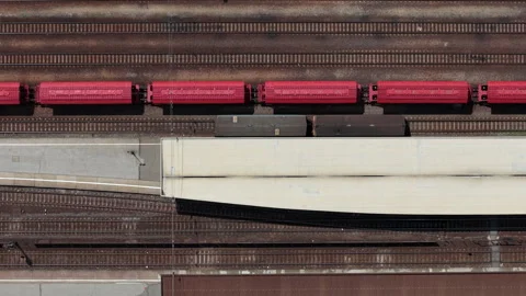 An aerial view of a red cargo train resting on railway tracks at a station in Stock Footage 337470439