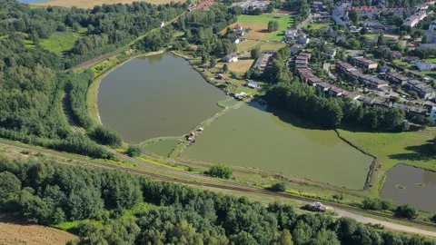 Aerial view of a red cargo train traveling through a rural landscape with lakes Stock Footage 348270124
