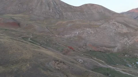 Aerial view of red eroded slopes above a village road, Gulcha, Kyrgyzstan Видео 347242034