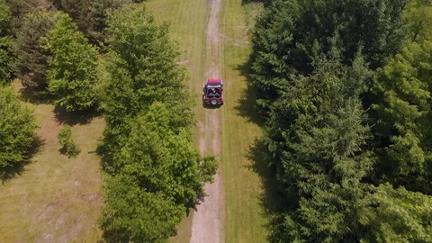 Aerial view of red Jeep driving off road in a forest. Cinematic drone shot Stock Footage