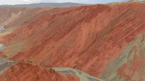 Aerial view of red layered canyon cliffs and muddy river in Xinjiang Stock Footage 345522010