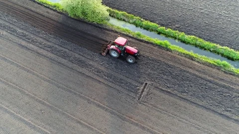 Aerial view of red modern tractor flattening the fresh plowed soil 4k Stock Footage 84990624