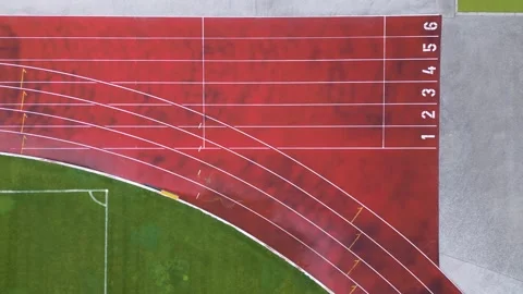 Aerial view of a red running track with marked lanes and curved lines. Athletic Stock Footage 309869589