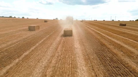 Aerial view of red square baler machinery baling straw on farmland after harvest Stock Footage 340510519