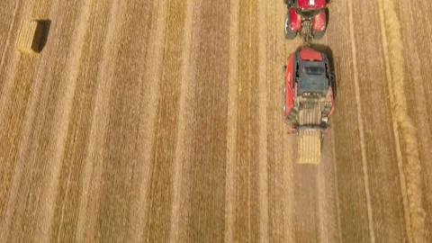 Aerial view of red square baler machinery baling straw on farmland after harvest Stock Footage 340511717