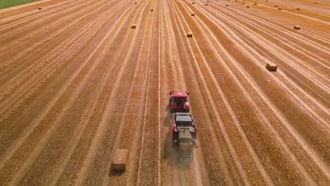 Aerial view of red square baler baling straw on farmland after harvest Stock Footage 340512266