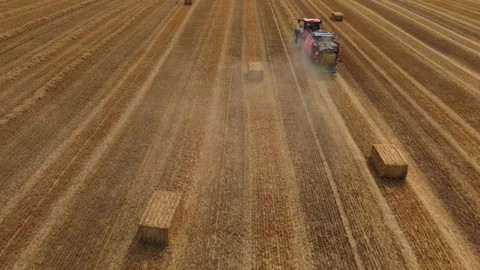 Aerial view of red square baler baling straw on farmland after harvest Stock Footage 340513420