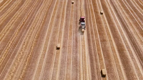 Aerial view of red square baler baling straw on farmland after harvest Stock Footage 340514766