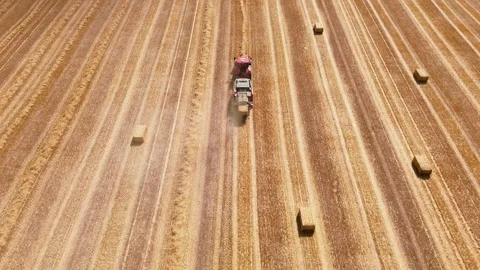 Aerial view of red square baler baling straw on farmland after harvest Stock Footage 340528211