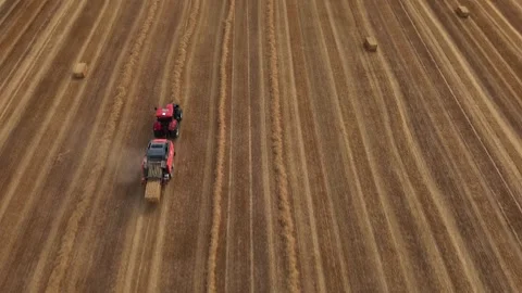 Aerial view of red square baler baling straw on farmland after harvest Stock Footage 340531383