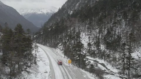 Aerial view of red SUV driving through heavy snowstorm in Tibet Vídeos de archivo 345179621