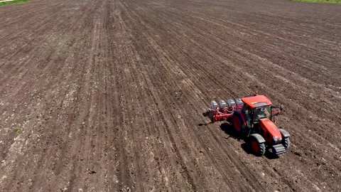 Aerial view of red tractor cuts furrows in farm field for sowing Stock Footage 246350227