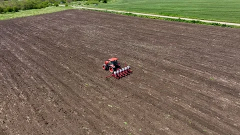 Aerial view of red tractor cuts furrows in farm field for sowing Stock Footage 246661275