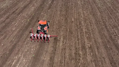 Aerial view of red tractor cuts furrows in farm field for sowing Stock Footage 247077769