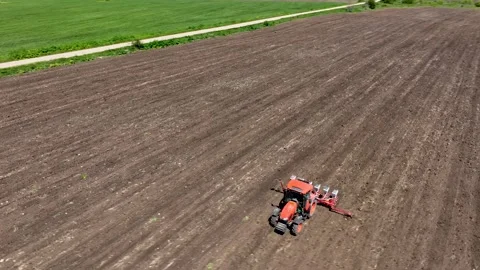 Aerial view of red tractor cuts furrows in farm field for sowing Stock Footage 252853157