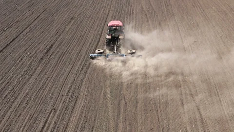 Aerial view red tractor with harrows prepares the dry field agricultural land. Video stock 128367135