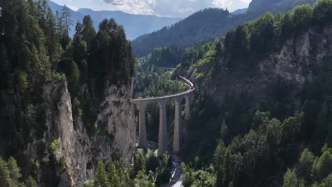 Aerial view of red train crossing the landwasser viaduct in switzerland Stock Footage 318364032