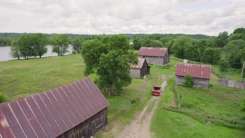 Aerial view of a red truck pulling up on a old farmland with a weathered wooden Stock Footage 317686480