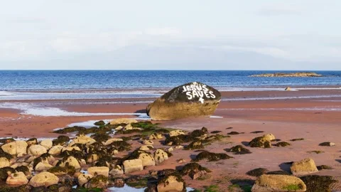 Aerial View Of Religious Message Painted On Large Beach Rock Vidéo 337781378