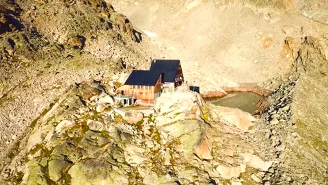 Aerial View of Remote Alpine Mountain Hut Next to Glacial Tarn Lake Stock Footage 346732994