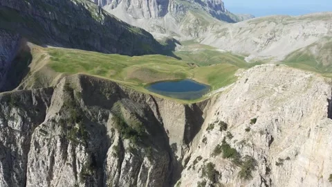 Aerial View of Remote Lake Surrounded by Rocky Mountains Stock Footage 303399605