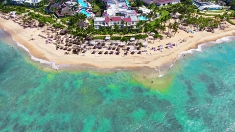 Aerial view of a resort's empty sandy beach with thatched umbrellas. Видео 329601610