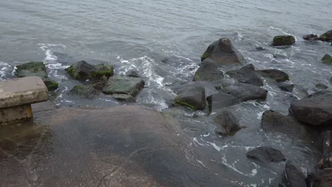 Aerial view of riptide foaming waves on the stone shore with rocks Stock Footage 302584280
