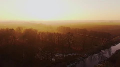 Aerial view of a river and bare forest during golden hour in winter Stock Footage 327814775