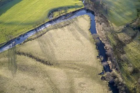 Aerial view of river and empty green meadow field Stock Photos