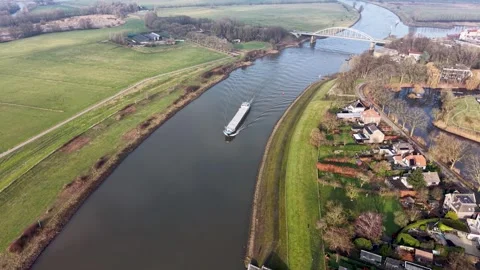 Aerial view of river bend with cargo vessel, docked boats, bridge and curved 库存影片 329192510